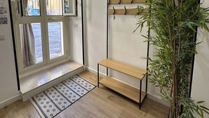 A room with a wooden bench, a bamboo plant, a patterned rug, and an air conditioning unit. - Scilló House (Palermo)