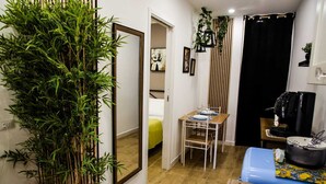 A compact room with a bed, a dining table set for two, a coffee machine, and a large mirror. - Scilló House (Palermo)