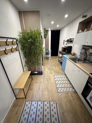 Une cuisine moderne avec un plancher en bois, un banc intégré, une grande plante en pot et un petit coin repas.