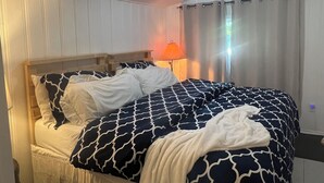 A bed with a patterned bedspread, a wooden headboard, and a bedside lamp with an orange shade.