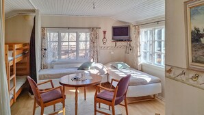 Ein gemütliches Zimmer mit einem Stockbett, einem runden Tisch mit Stühlen, einem Fernseher und einem Bild an der Wand.