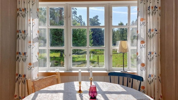 Ein Zimmer mit großem Fenster, einem Tisch mit Kerzen und einem Stuhl.