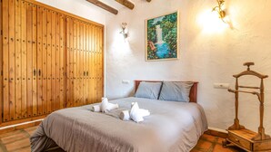 A bedroom with a wooden wardrobe, a bed with a grey bedspread, two pillows, and a wooden nightstand with a lamp. - Beautiful home in Alora with WiFi (Alora)
