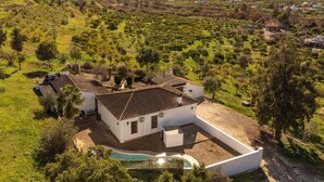 A white villa with a tiled roof, surrounded by lush greenery and a swimming pool. - Beautiful home in Alora with WiFi (Alora)