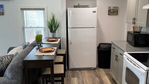 A modern kitchen with a refrigerator, stove, and microwave. There is a dining table with chairs and a potted plant. - Cozy, Clean & Convenient 1-bedroom apartment with AC & WiFi in charming Clayton (Clayton)