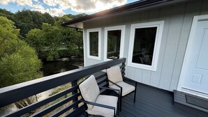 Une terrasse avec deux chaises et une rambarde donnant sur une rivière et la verdure.