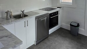 A modern kitchen with white cabinets, a stainless steel sink, a dishwasher, and an oven. - Magpie Cottage. Newly Renovated , 2 Bed, 2 bathroom close to Napier CBD (Napier)