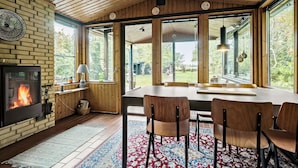 A cozy room with a fireplace, large windows, and a dining area with chairs. - Nice home in Gørlev with WiFi (Gørlev)