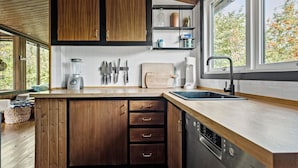 A modern kitchen with wooden cabinets, a built-in dishwasher, a sink, and a window overlooking greenery. - Nice home in Gørlev with WiFi (Gørlev)