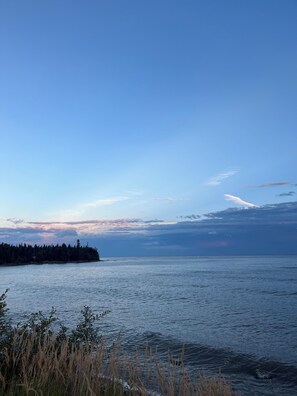 Un lac paisible, avec une île boisée qui se dessine à l’horizon et un ciel dégagé.