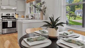 A modern kitchen with a central island, stainless steel appliances, and a view of a residential neighborhood. - Luxurious 4BD near Downtown and RDU, with sunroom, theatre, games, & more! (Raleigh)