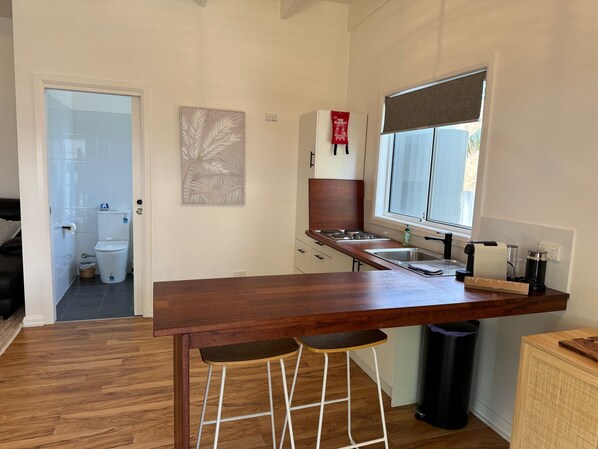 Une cuisine moderne avec un plan de travail en bois, une fenêtre et une vue sur la salle de bain adjacente.