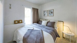Ein Schlafzimmer mit einem Bett, einem Nachttisch, einer Lampe und zwei gerahmten Bildern an der Wand.