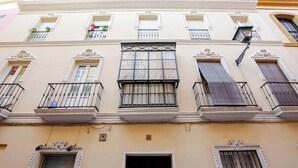 Un immeuble doté de nombreux balcons, d’une fenêtre centrale à croisillons et d’une porte avec un cadre en bois foncé.