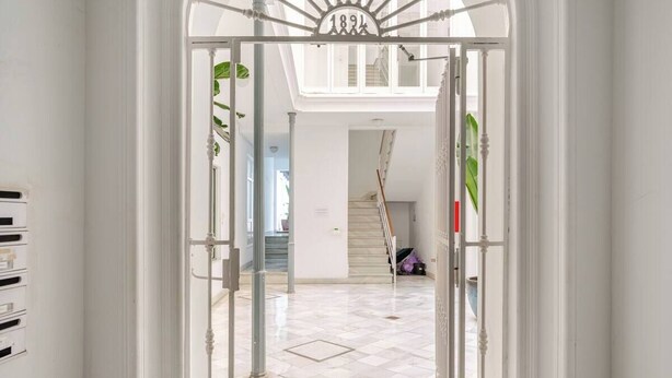 Un hall d’entrée spacieux avec une porte blanche donnant sur un escalier.
