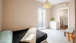A bedroom with a bed, a bedside table, a hanging lamp, a wardrobe, and a view of the bathroom.