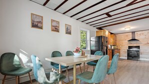Un comedor con mesa y sillas, una cocina con armarios de madera, y un techo con vigas a la vista.