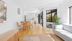 Un salon moderne comprenant un canapé, une table basse en bois et un coin repas avec des chaises et une table.