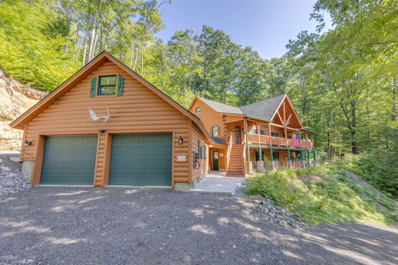 A log cabin with a large garage, a covered porch, and a second-story balcony.
