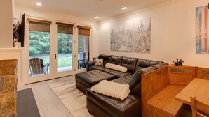 A cozy living room with a leather sofa, a wooden bench, and a dining table.