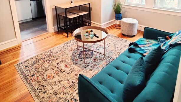 A modern living room with a teal sofa, a coffee table, and a patterned rug. - 1601 Lombard  (Philadelphia)