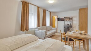 Ett litet rum med en säng, en soffa, ett matbord och ett litet kök.