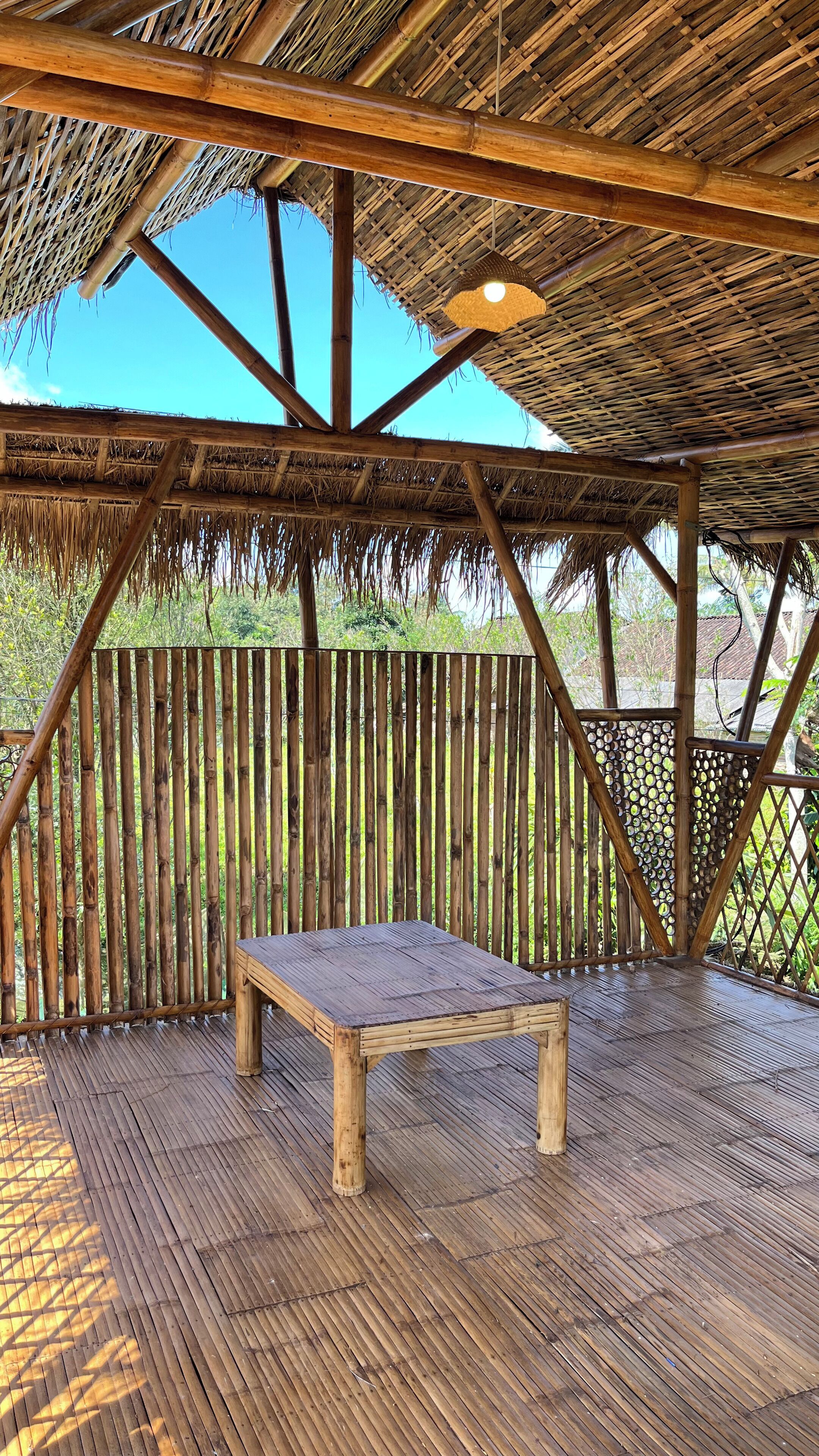 A wooden deck with a thatched roof structure and a table.