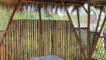 A wooden deck with a thatched roof structure and a table.