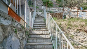Eine Steintreppe mit Metallgeländern, die einen felsigen Hügel hinaufführt.