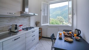 Eine moderne Küche mit Gasherd, Kaffeemaschine und einem Esstisch, gedeckt mit Frühstücksgebäck.