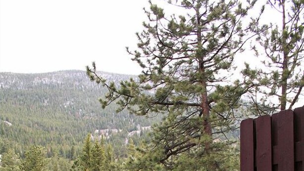 Ein Whirlpool mit einer Holzterrasse und Blick auf eine bewaldete Bergkette.
