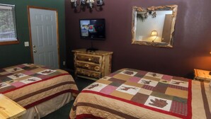 A room with two beds, a wooden dresser, a television, and a mirror on the wall. - One bedroom Chalet with Personal Hot Tub (Estes Park)