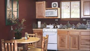 A kitchen with wooden cabinets, a white stove, a microwave, and a window with blinds.