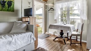 A cozy room with a wooden ceiling, a white sofa, a table with a polka dot tablecloth, and a chair.