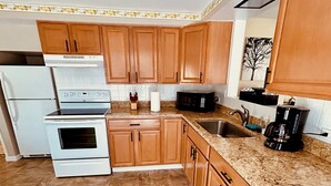 A kitchen with wooden cabinets, a granite countertop, a stainless steel sink, a stove, and a microwave. - 2-bedroom apartment just a short walk from the Saint Lawrence River.
 (Clayton)