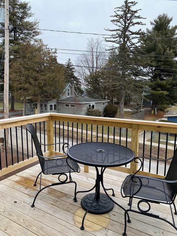 A wooden deck with a round table and two chairs, overlooking a residential area with houses and trees. - 2-bedroom apartment just a short walk from the Saint Lawrence River.
(Clayton)