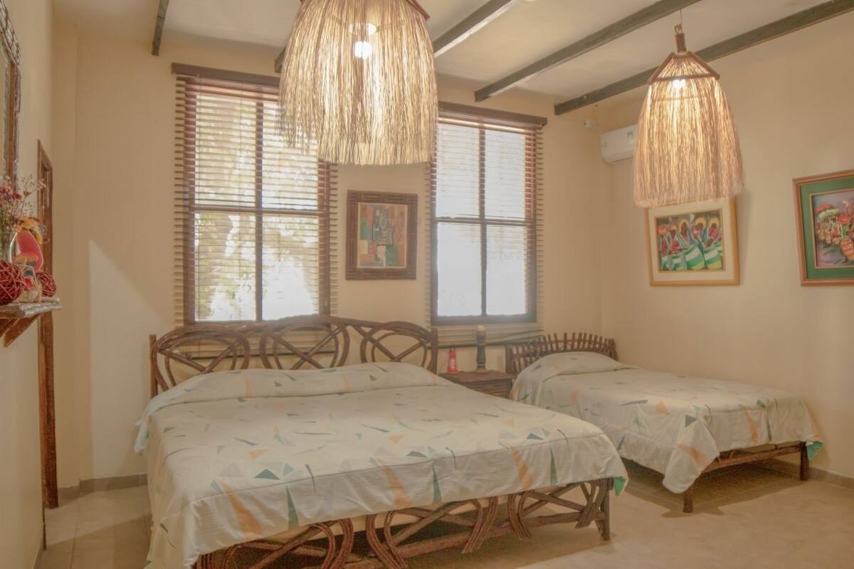 A room with two wooden beds, wicker chairs, and a hanging light fixture.