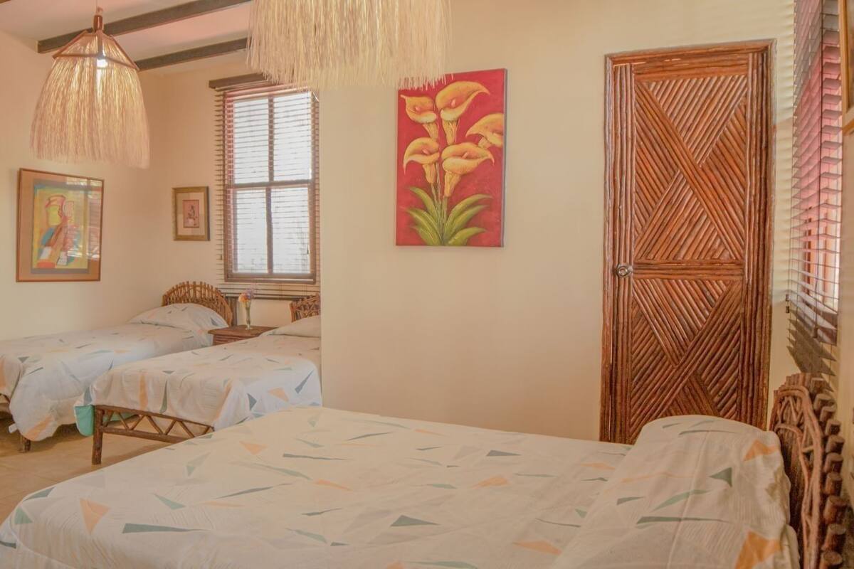 A room with two beds, a wooden door, and a window with blinds.