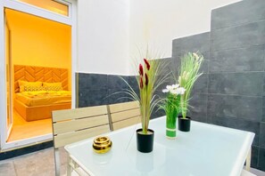 A room with a bed, a table with two potted plants, and a chair.