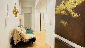 A modern interior with a bed, a wall-mounted lamp, and a large abstract painting. - Ottakring Gem 4-BR Retreat/Breathtaking City Views (Vienna)