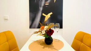 A dining table with a vase of flowers, two chairs, and a wall art piece. - Ottakring Gem 4-BR Retreat/Breathtaking City Views (Vienna)