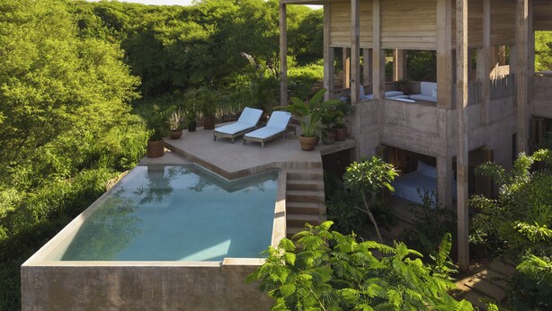 A modern outdoor pool area with lounge chairs and potted plants.