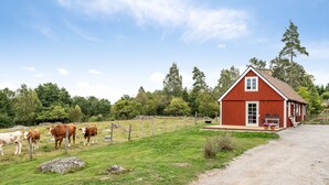 A red barn with a porch and a gravel driveway.