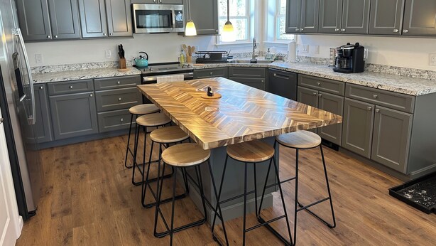 A modern kitchen with a large island, bar stools, and a coffee machine. - ADK cottage with Mountain Views  (Saranac)