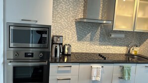 A modern kitchen with stainless steel appliances, a tiled backsplash, and white cabinetry. -  Breathtaking view, as well as modern, clean & well-appointed apartment 
 

 (Toronto)