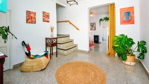 Een modern interieur met een trap, een geweven bank en potplanten.
