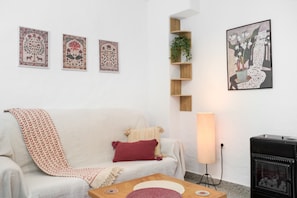 A living room with a sofa, a coffee table, a fireplace, and wall art. - Holiday Home 'La Casa De Eva' with Mountain View, Shared Terrace and Wi-Fi (Gaucín)