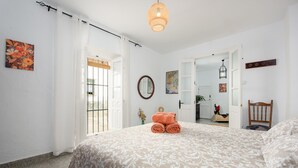 Een slaapkamer met een bed, een spiegel en een deur naar een andere kamer.