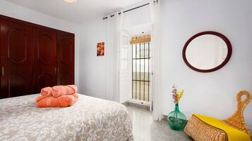A bedroom with a bed, a wardrobe, a mirror, a window with a view, and a door leading to an outdoor area.