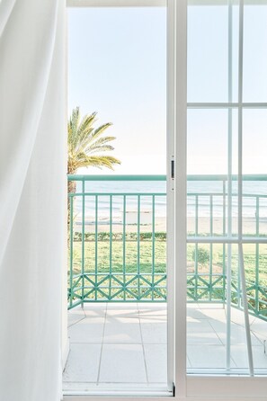 A balcony with a view of the beach and palm trees. - Apartment 'Strand Appartement Met Zwembad Td04' with Sea View, Wi-Fi and Air Conditioning (Torrox)